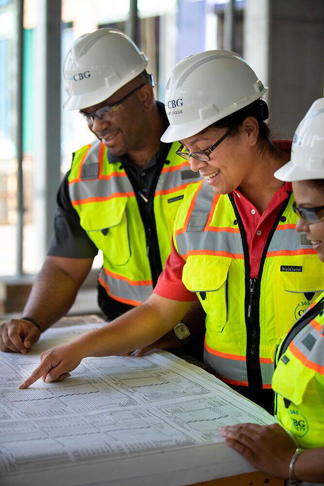 Male and female CBG construction workers point to a site map.