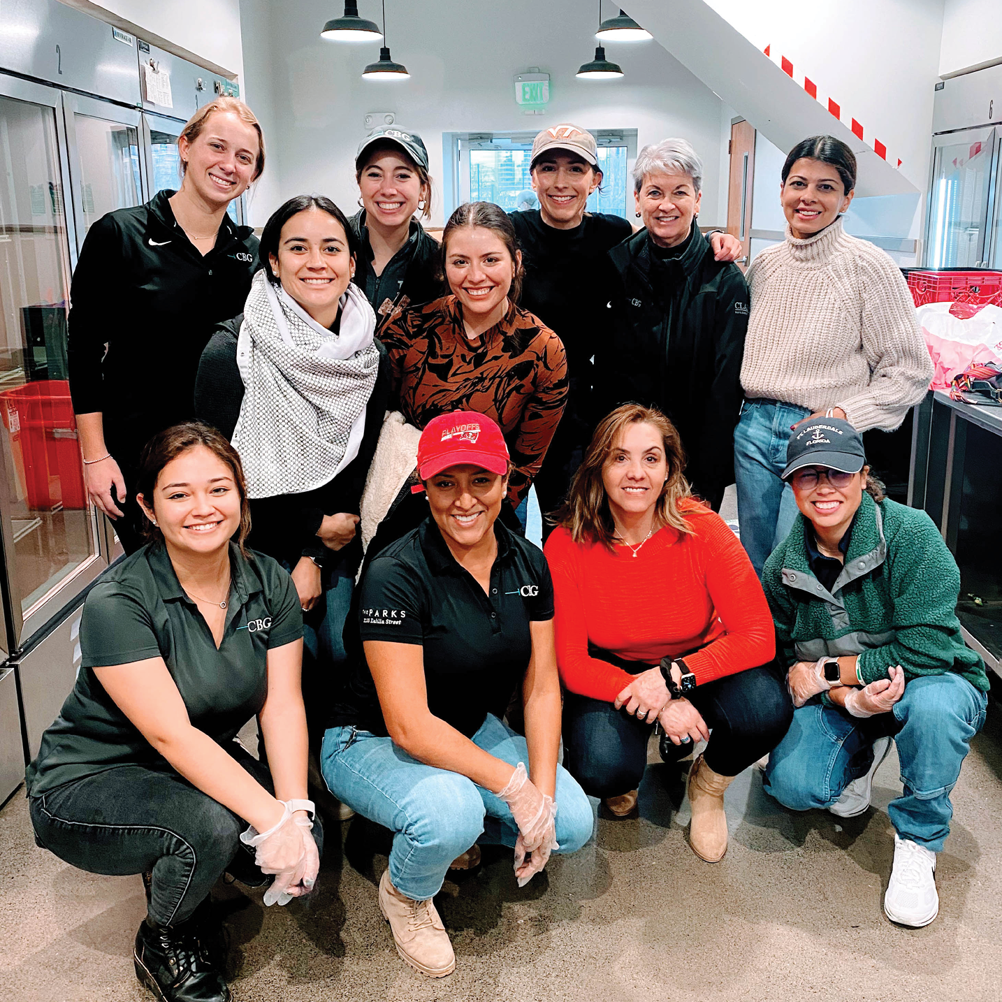 A diverse group of women employees from CBG Building Company smiling together at a community service and volunteering event.