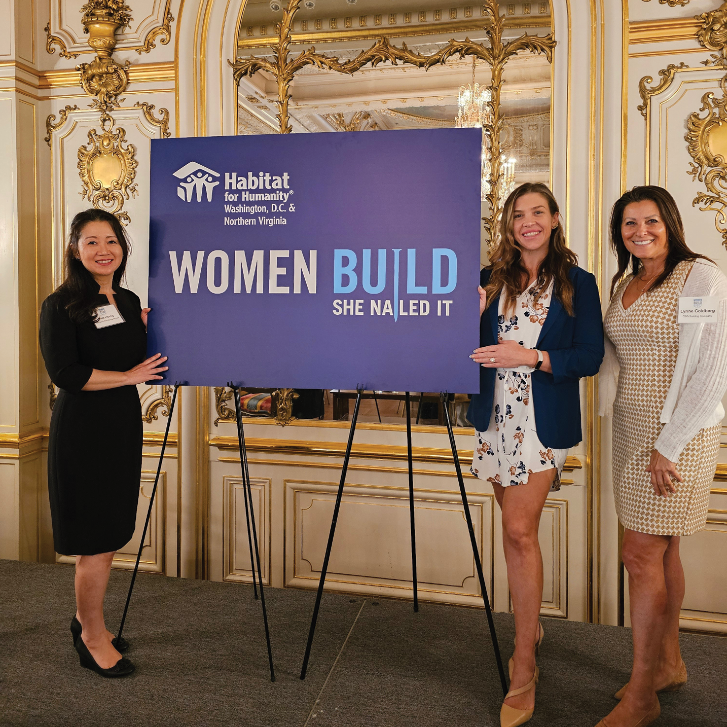Three female construction professionals standing next to a Habitat for Humanity Washington, D.C. & Northern Virginia Women Build sign.
