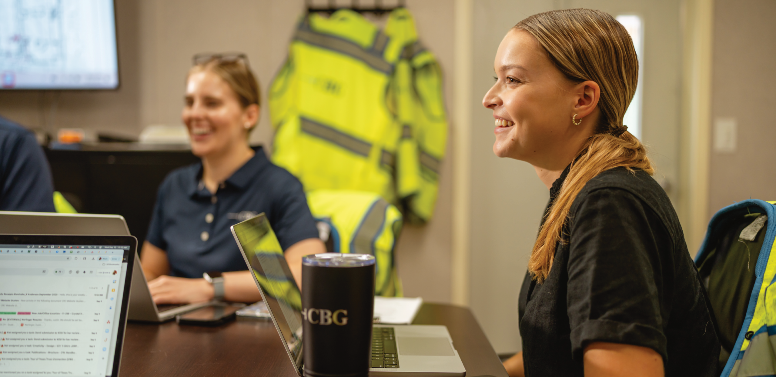 Two smiling female construction project managers collaborating during an office meeting at CBG Building Company.